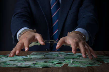 business crime concept, handcuffed criminal in suitの写真素材