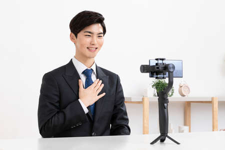 Asian young man in suit preparing untact online interview using smartphoneの写真素材