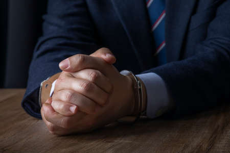 business crime concept, handcuffed criminal in suitの写真素材