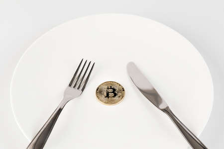 knife, fork and bitcoin on plate