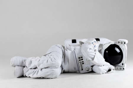 Astronaut lying on side, white background