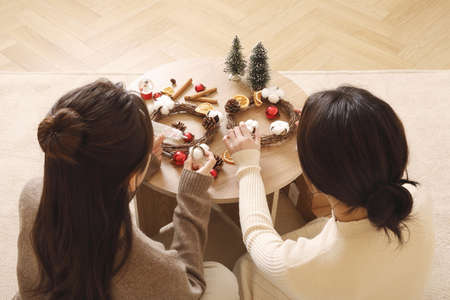asian korean women spending time indoors making christmas wreathの写真素材