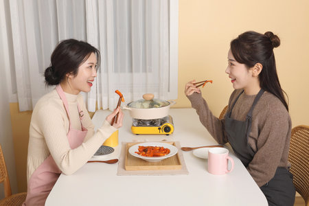asian korean women eating after cooking together, spending time indoors, social distance in winterの写真素材