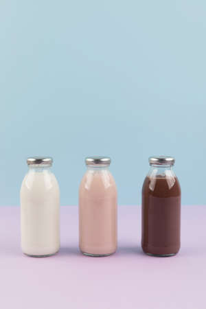white milk, strawberry milk, chocolate milk in a sky blue and purple backgroundの写真素材