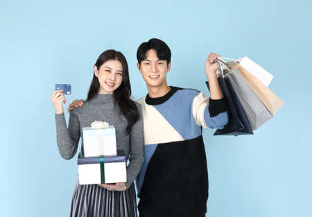 Asian Korean couple with shopping bag, gift box and credit cardの写真素材