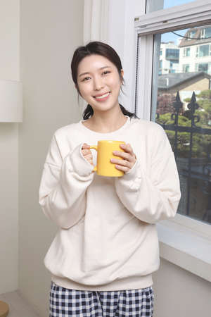 asian woman drinking tea by the window