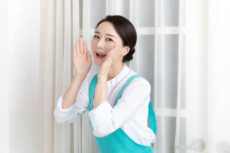 Asian woman wearing white shirt and apron, professional home cleaning service job