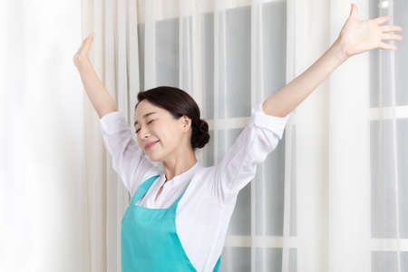 Asian woman wearing white shirt and apron, professional home cleaning service jobの写真素材