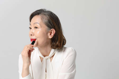 Asian Korean senior woman, bold and red cosmetics makeup beauty concept in studioの写真素材