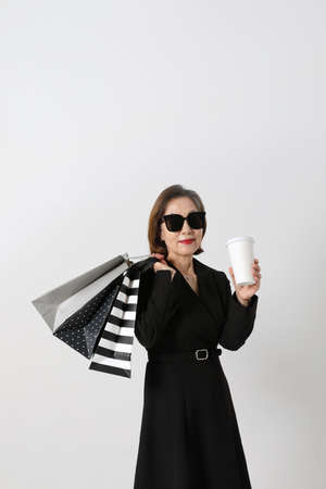 fashionable Asian Korean senior woman, holding a coffee and shopping bagの写真素材