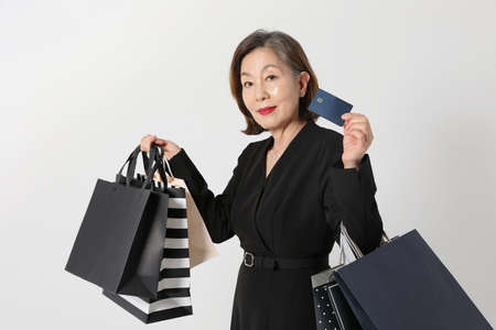 fashionable Asian Korean senior woman, holding a credit card and shopping bag