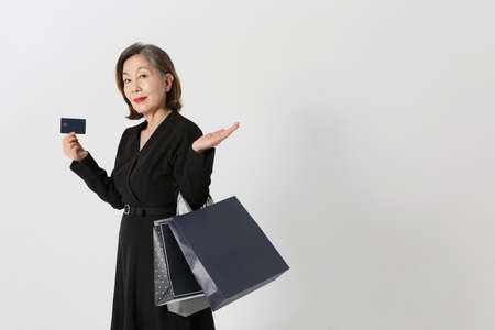 fashionable Asian Korean senior woman, holding a credit card and shopping bagの写真素材