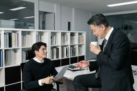 business concept asian korean old and young two men, different generations male man boss and employee concept, talking drink coffeeの写真素材