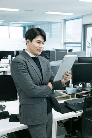 business concept asian korean old and young two men, different generations male man boss and employee concept, watching tabletの写真素材