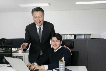 business concept asian korean old and young two men, different generations male man boss and employee concept, using laptopの写真素材