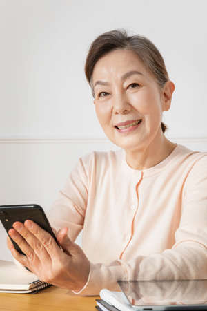 Asian Korean senior woman watching smartphoneの写真素材