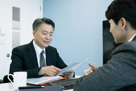 business concept asian korean old and young two men, different generations male man boss and employee concept, talking, having a meeting on document, projectの写真素材