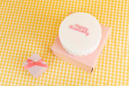 happy birthday lettering cake and gift box, yellow checkered fabric background