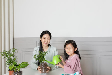 Asian Korean mom and daughter watering recycled potsの写真素材