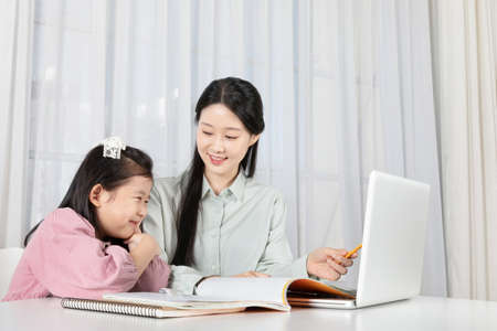 Asian Korean mother and daughter taking online classes on laptopの写真素材
