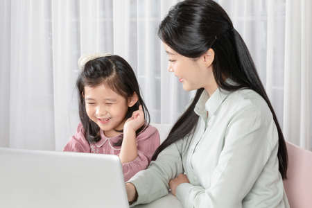 Asian Korean mother and daughter taking online classes on laptopの写真素材