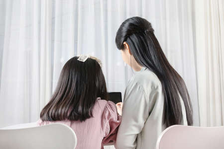 Asian Korean mother and daughter taking online classes on tablet