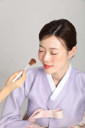 spring beauty concept, beautiful korean woman wearing hanbok getting makeupの写真素材