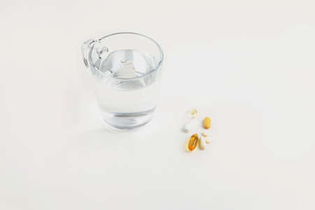 a cup of water and a pills, white background, medical creative concept photoの写真素材