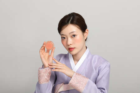 spring beauty concept, beautiful korean woman wearing hanbok with holding blusherの写真素材