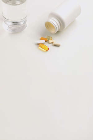 a cup of water and a pills, white background, medical creative concept photoの写真素材