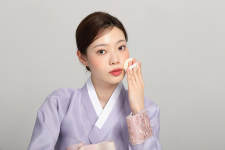 spring beauty concept, beautiful korean woman wearing hanbok getting her makeupの写真素材