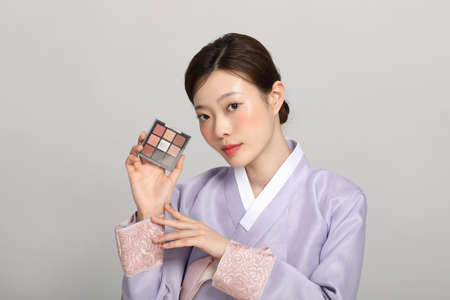 spring beauty concept, beautiful korean woman wearing hanbok with holding an eyeshadowの写真素材