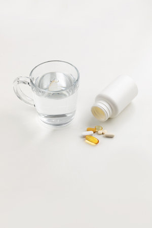 a cup of water and a pills, white background, medical creative concept photoの写真素材