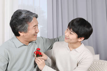 Asian Korean family_Grandchildren giving carnations to grandparentsの写真素材