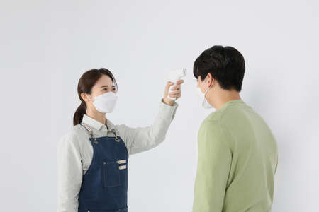Asian Korean young man and woman startup concept_ checking their body temperature with a thermometer