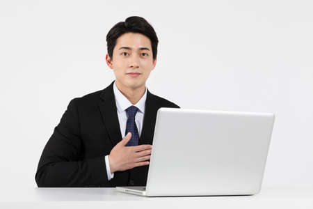 Asian Korean young man and woman startup concept wearing smart business suit_a young man taking a online interview with a laptopの写真素材