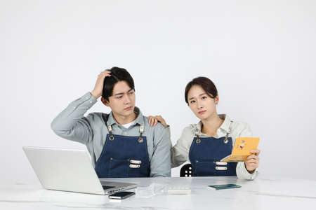Asian Korean young man and woman startup concept_ are worried while looking at their bankbooksの写真素材