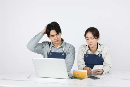 Asian Korean young man and woman startup concept_ are worried while looking at their bankbooksの写真素材