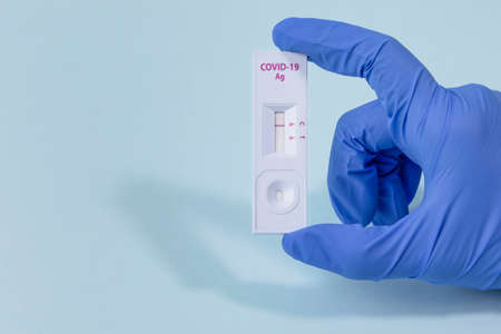 hands checking covid test kit with negative result, blue backgroundの写真素材