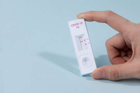 hands checking covid test kit with negative result, blue background