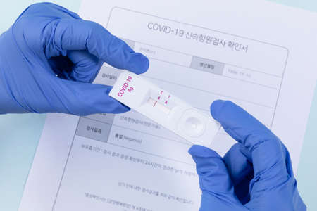 hands checking covid test kit and paper with negative result, blue backgroundの写真素材