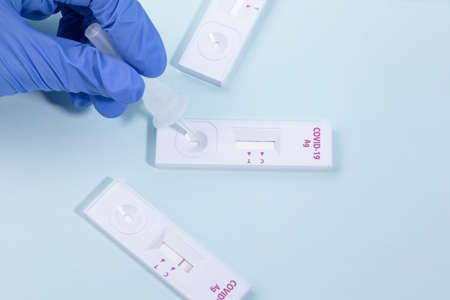 hand dropping specimen solution into the covid test kit, blue backgroundの写真素材