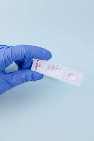 hands checking covid test kit with negative result, blue background