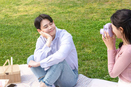Asian Korean couple enjoying spring picnic, taking a selfieの写真素材