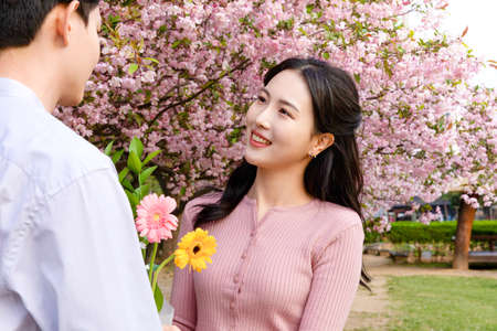Korean Asian couple enjoying spring date, holding flowersの写真素材