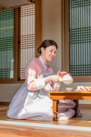 Korean and Caucasian girls experiencing traditional tea ceremony in Hanok, Korean traditional house