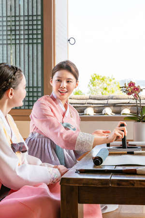 Korean and Caucasian girls Experiencing traditional calligraphy in Hanok, Korean traditional houseの写真素材