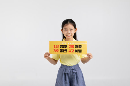 Korean young girl wearing gym clothes in white background studio__holding a drive safe copyspace panelの写真素材