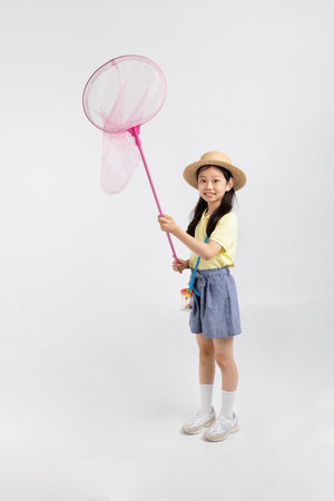Korean young girl wearing gym clothes in white background studio__holding a catch dragonflyの写真素材