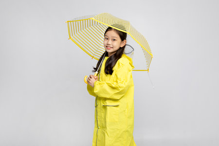 cute young Korean girl, rainy season concept in white background studio__wearing raincoat and umbrellaの写真素材
